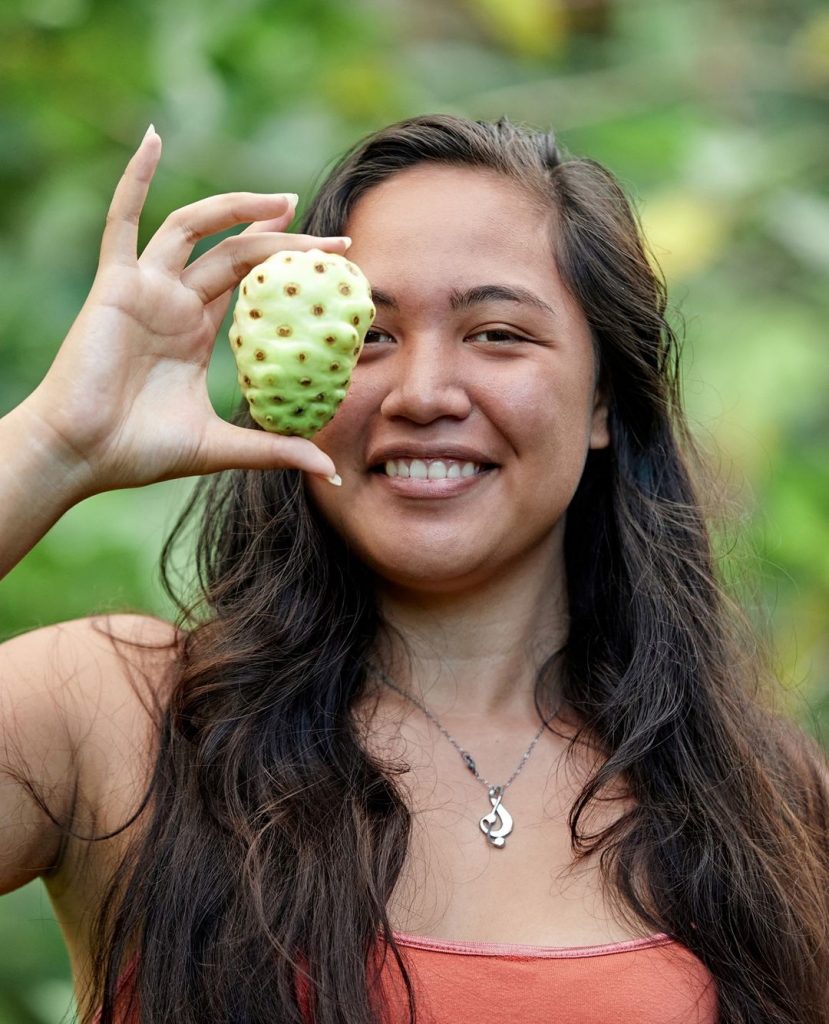 woman holding up Noni fruit