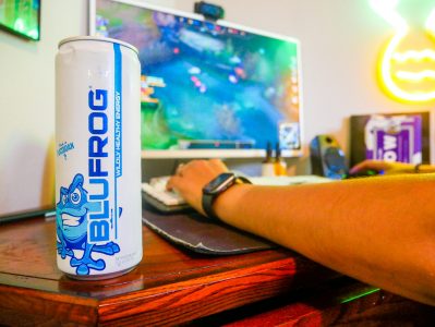 photo of blufrog energy drink on desk with gamer playing